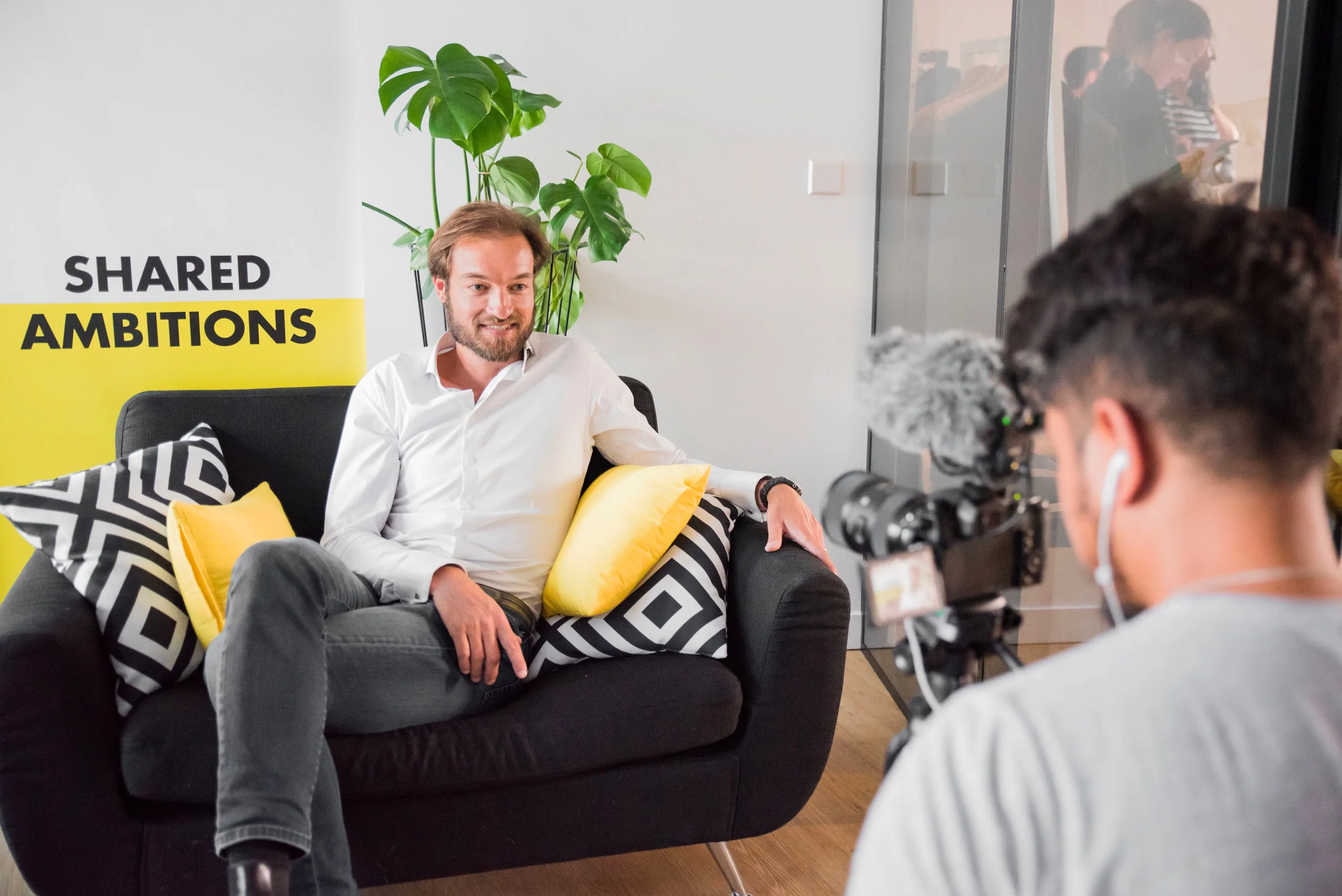 Tournage d’une interview en entreprise : un dirigeant assis dans un fauteuil face à un vidéaste et sa caméra