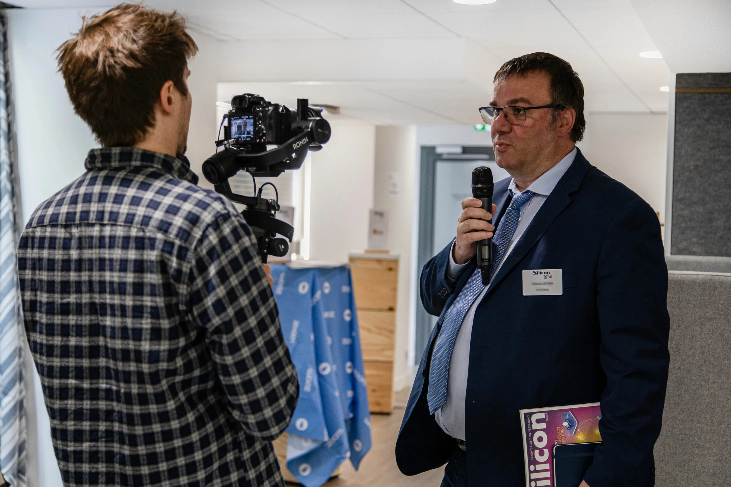 Vidéaste filmant l’interview d’un participant lors d’un évènement professionnel, micro à la main