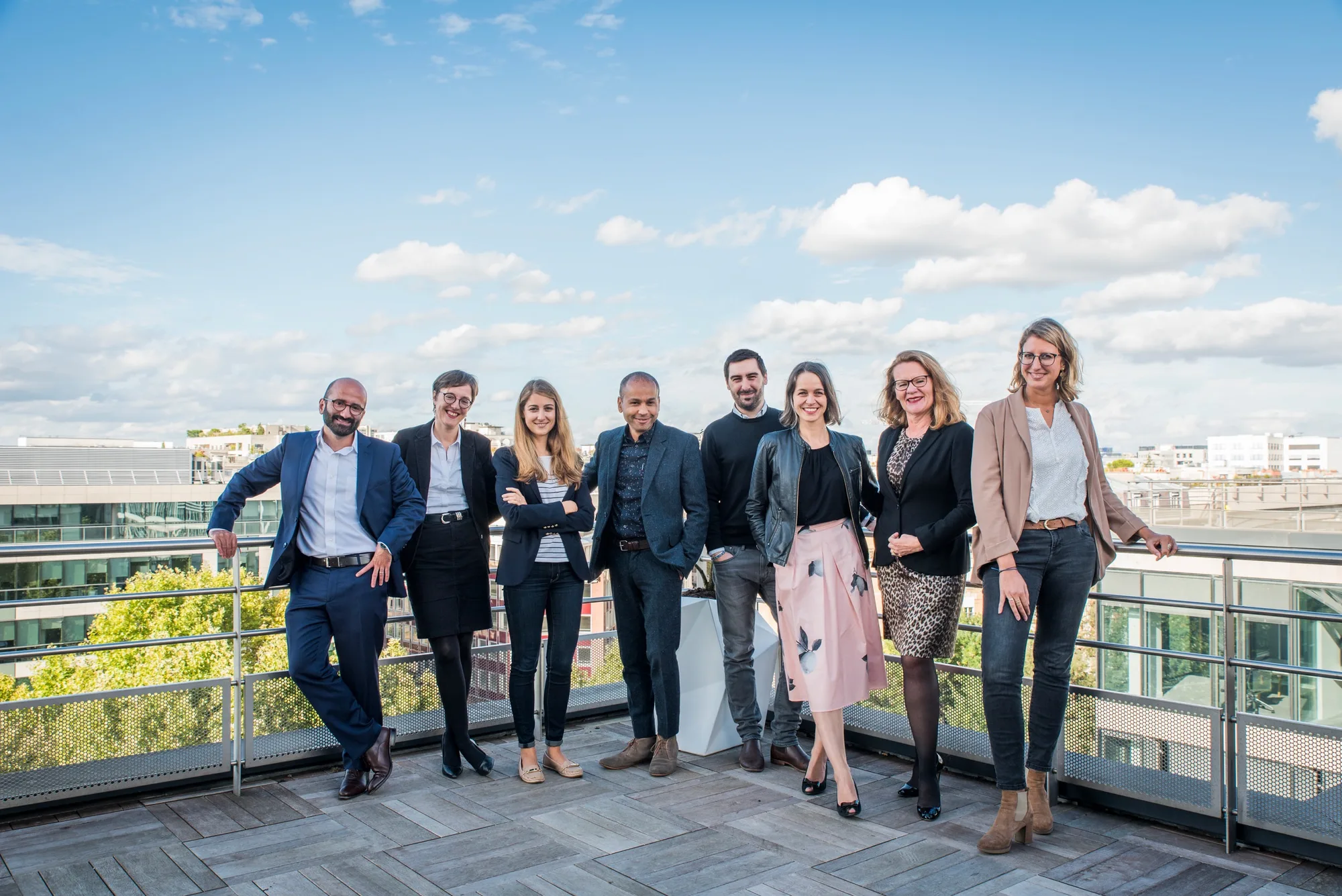 Photo de groupe d’une équipe d’entreprise sur une terrasse en toit-terrasse, ciel dégagé sur les toits
